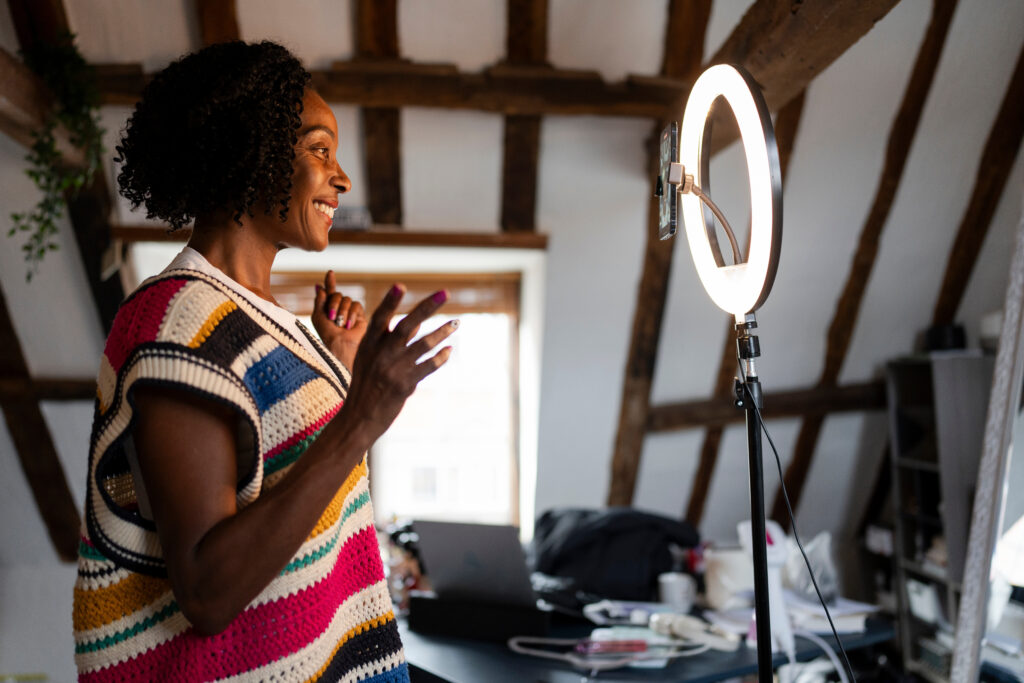 Smiling woman recording live-streaming video at home