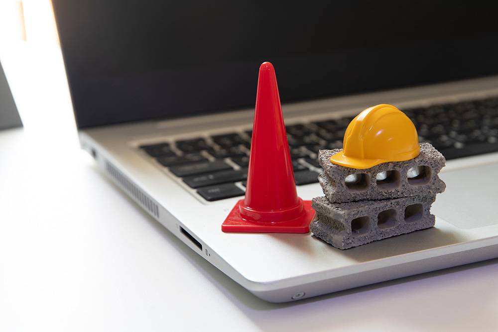 tiny red cone and construction equipment on a computer representing website maintenance